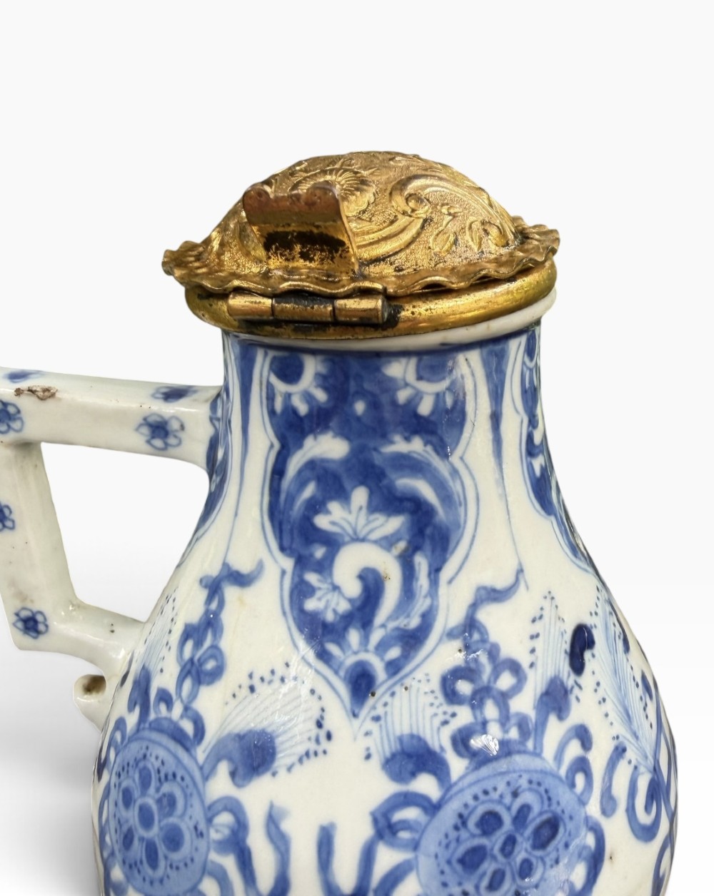 A blue and white Kangxi period Chinese porcelain jug with hand-painted floral decoration, an angular ceramic handle, and a chased gilt-metal lid. View IX