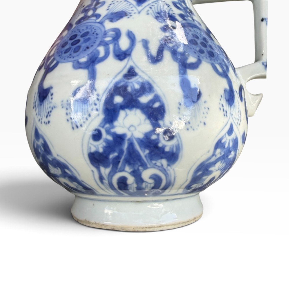 A blue and white Kangxi period Chinese porcelain jug with hand-painted floral decoration, an angular ceramic handle, and a chased gilt-metal lid. View XII