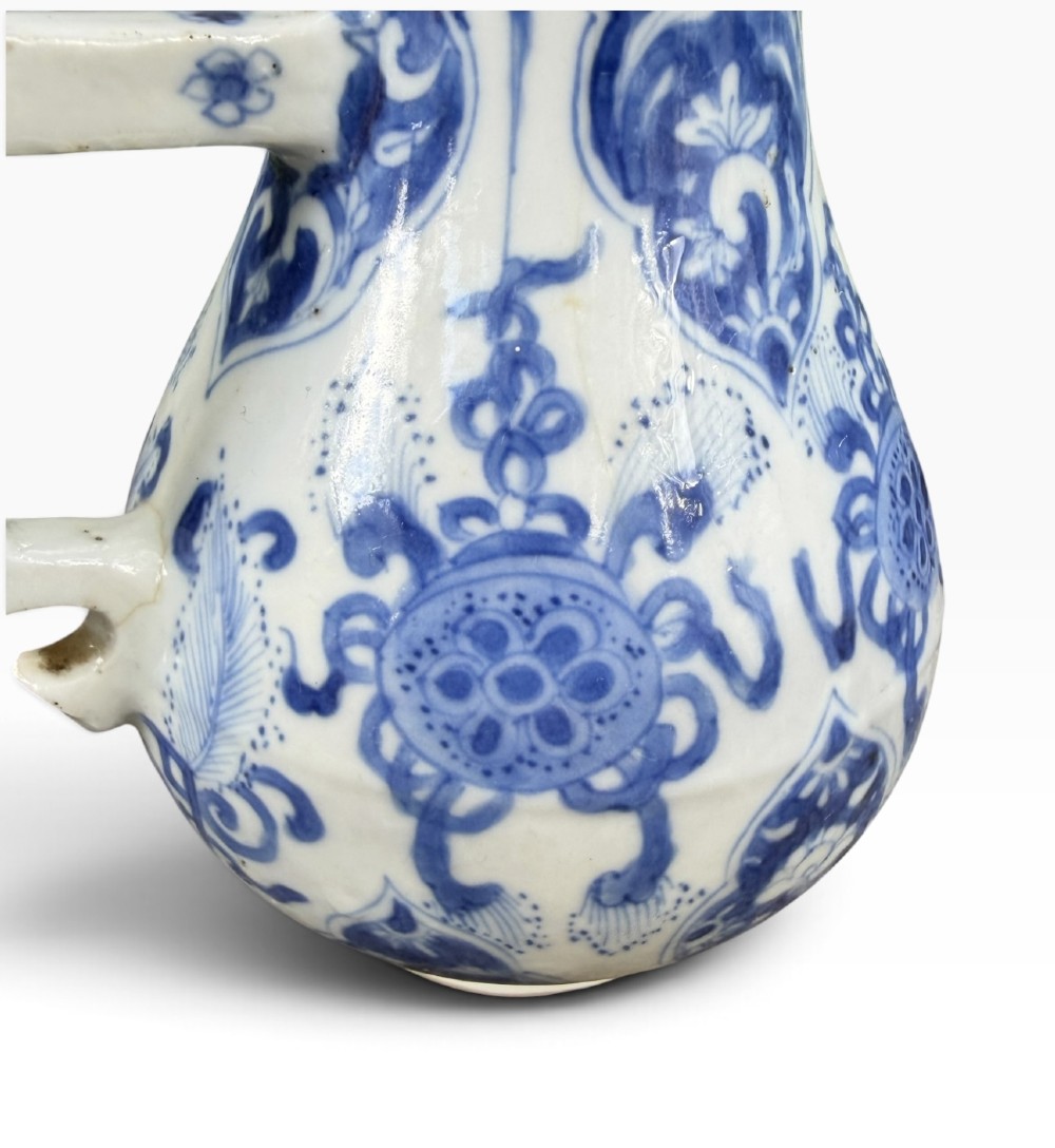 A blue and white Kangxi period Chinese porcelain jug with hand-painted floral decoration, an angular ceramic handle, and a chased gilt-metal lid. View XIV