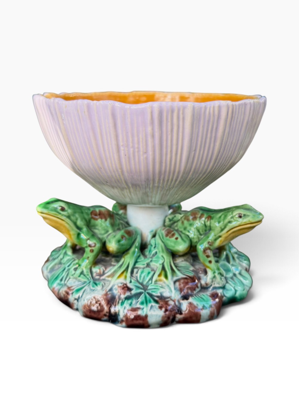 A Victorian Minton majolica footed bowl featuring three-dimensional green frogs on a leafy base supporting a fluted lilac flower-form bowl with a yellow glazed interior.