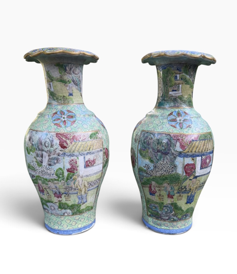 A pair of 19th-century Chinese Yixing stoneware baluster vases decorated in vibrant polychrome enamels with figural panels on a patterned green ground.