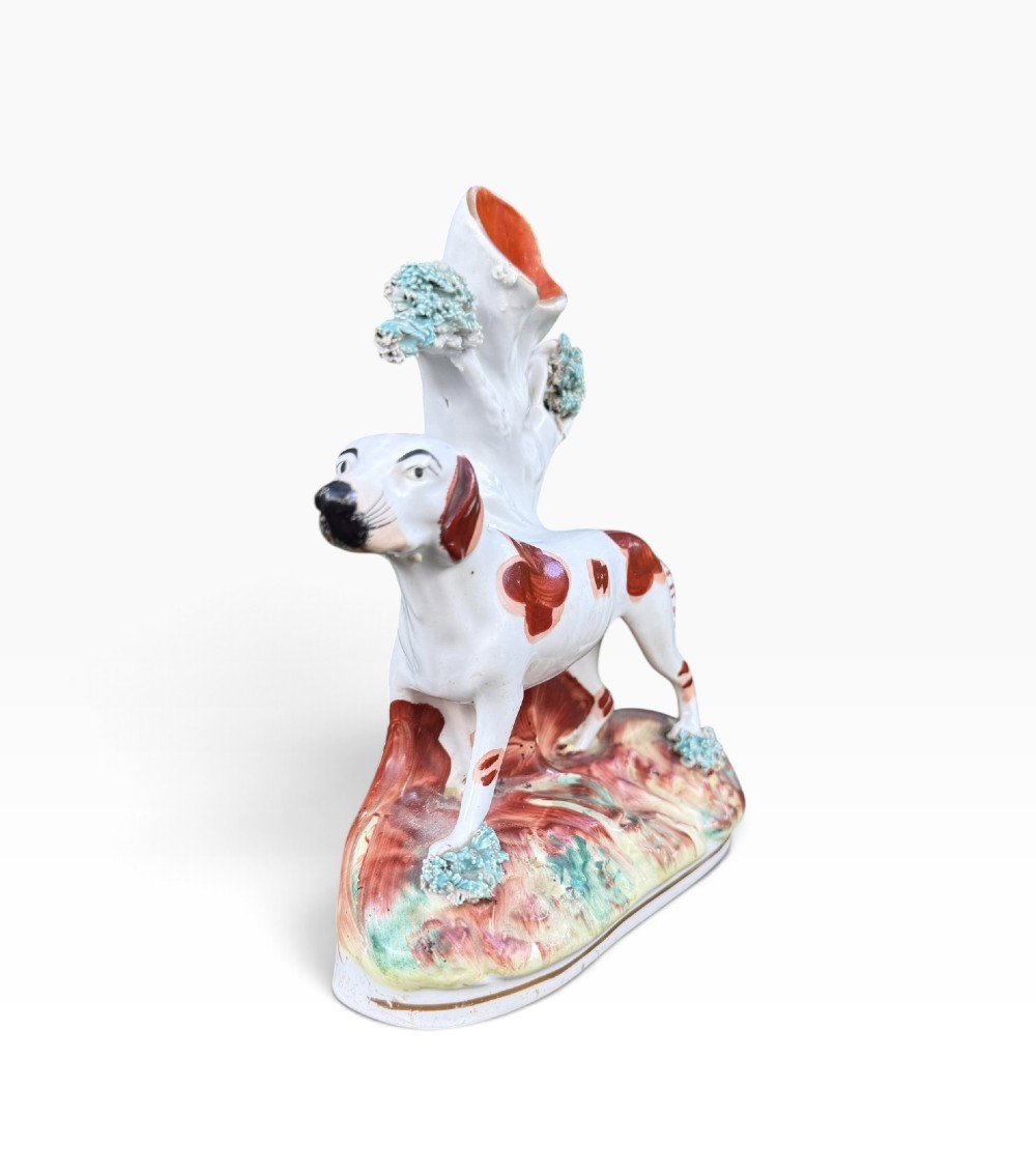 A Victorian Staffordshire pottery spill vase featuring a white and brown pointer dog standing in front of a tree trunk on a moulded base. View II