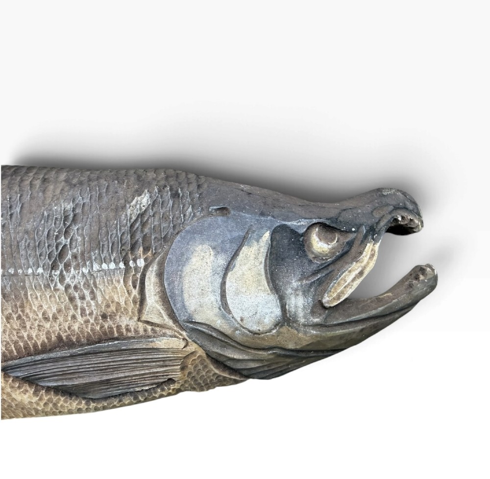 A realistic hand-carved wooden sculpture of a salmon with detailed scales and an open mouth, finished in muted grey and brown tones. View II