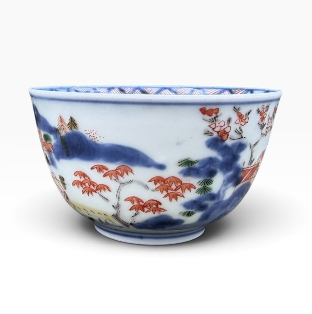 A small Japanese porcelain teabowl decorated with hand-painted figures, foliage, and landscapes in blue, red, green, and yellow enamels. View III