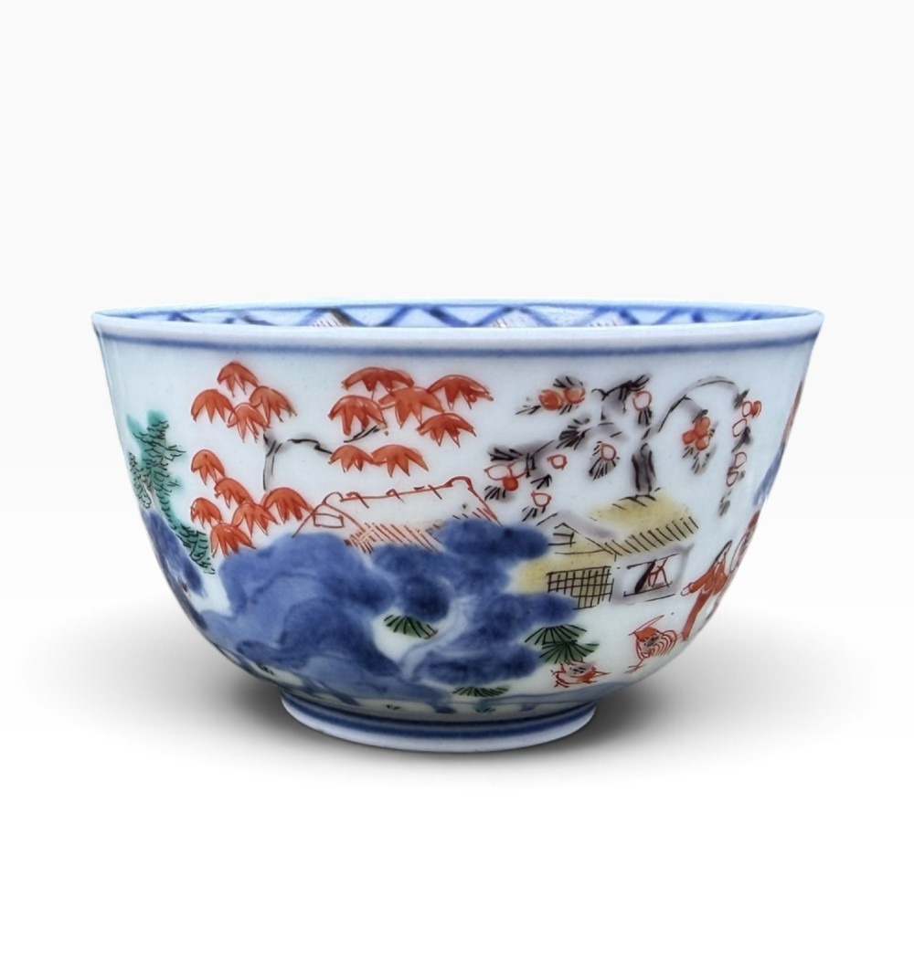 A small Japanese porcelain teabowl decorated with hand-painted figures, foliage, and landscapes in blue, red, green, and yellow enamels. View V