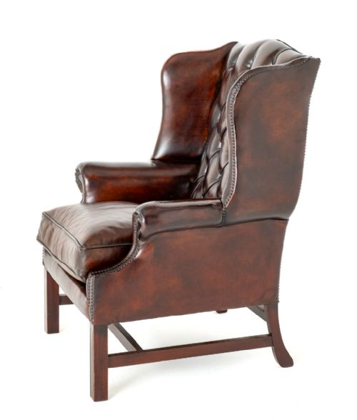 fig 2. A deep chestnut brown leather wingback armchair featuring deep buttoning, brass stud trimming, and square wooden legs with stretchers.