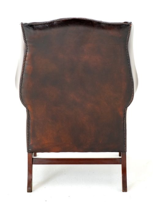 fig 3. A deep chestnut brown leather wingback armchair featuring deep buttoning, brass stud trimming, and square wooden legs with stretchers.