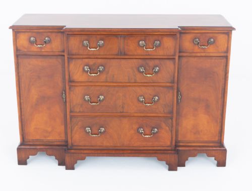fig 2. A Georgian Revival walnut breakfront sideboard featuring central drawers flanked by cupboard doors with brass handles and bracket feet.