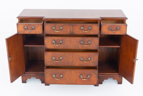 fig 1. A Georgian Revival walnut breakfront sideboard featuring central drawers flanked by cupboard doors with brass handles and bracket feet.