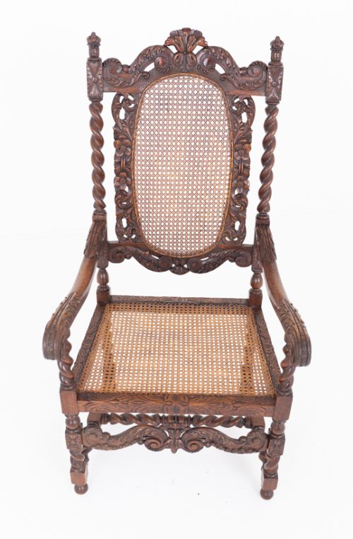 fig 1. A pair of carved dark oak armchairs featuring barley twist legs, oval cane backrests, and red velvet cushions.