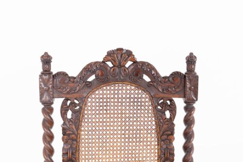 fig 2. A pair of carved dark oak armchairs featuring barley twist legs, oval cane backrests, and red velvet cushions.