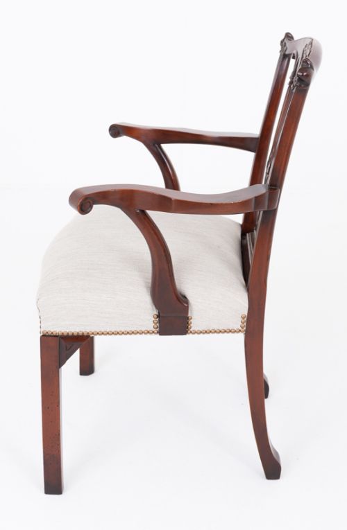 fig 2. A set of twelve carved mahogany dining chairs in the Gothic Revival style, featuring ten side chairs and two carvers with neutral upholstered seats.