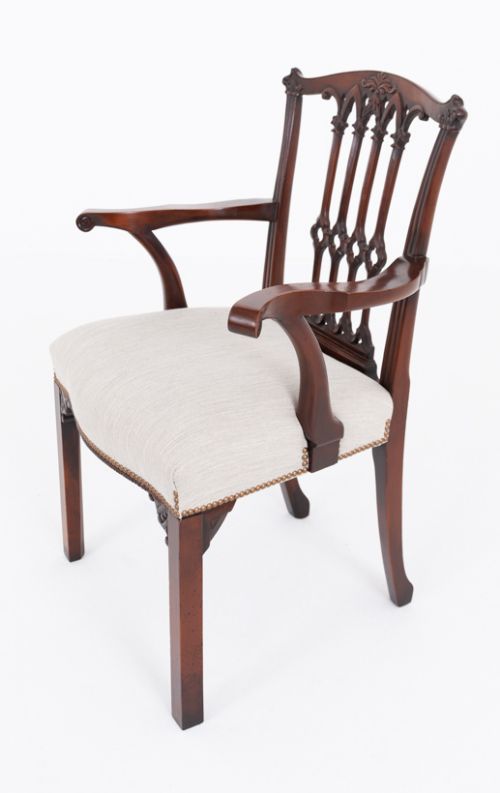 fig 3. A set of twelve carved mahogany dining chairs in the Gothic Revival style, featuring ten side chairs and two carvers with neutral upholstered seats.