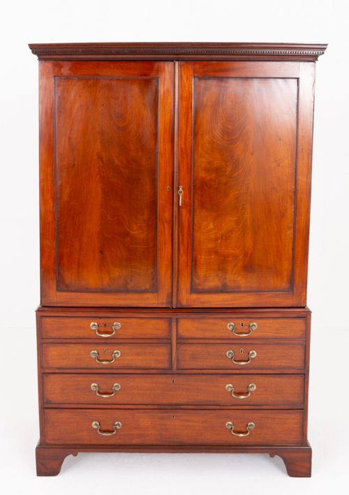 fig 1. A Georgian flame mahogany linen press with twin panelled cupboard doors, brass keyplates, a lower chest of four drawers with brass handles, and bracket feet.
