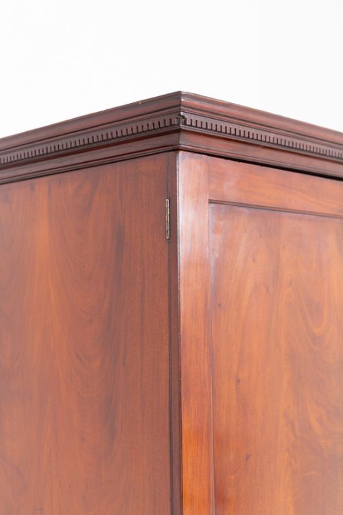 fig 2. A Georgian flame mahogany linen press with twin panelled cupboard doors, brass keyplates, a lower chest of four drawers with brass handles, and bracket feet.