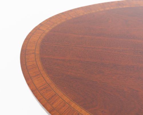 fig 1. An oval mahogany coffee table featuring a crossbanded inlaid top, turned central pedestal, four splayed legs, and brass cap castors.