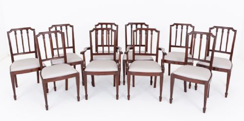 fig 1. A set of ten mahogany dining chairs featuring vertical splat backs, tapered legs with spade feet, and neutral patterned upholstered seats.