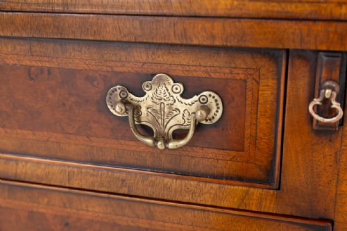 fig 1. A Georgian Revival walnut bachelors chest featuring four graduated drawers with brass handles, crossbanded inlay, and bracket feet.