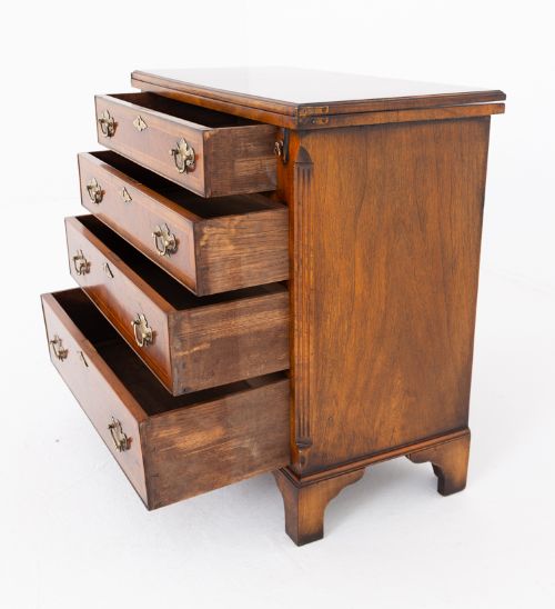fig 2. A Georgian Revival walnut bachelors chest featuring four graduated drawers with brass handles, crossbanded inlay, and bracket feet.