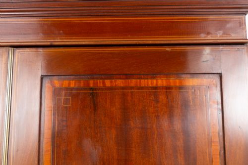fig 2. A tall Sheraton Revival mahogany two-door wardrobe featuring inlaid panelled doors, a lower base drawer, and bracket feet.