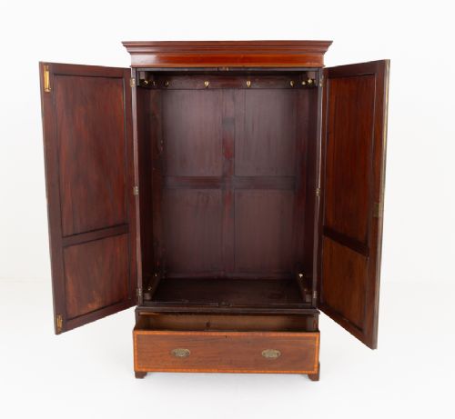 A tall Sheraton Revival mahogany two-door wardrobe featuring inlaid panelled doors, a lower base drawer, and bracket feet. View VI