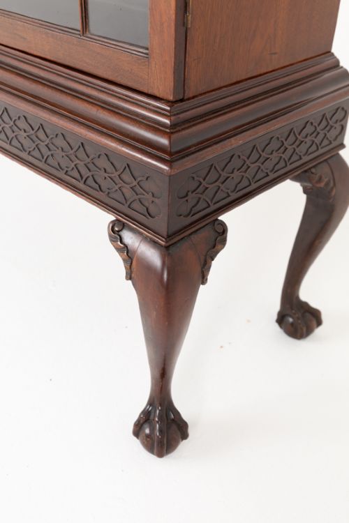 A mahogany Chippendale style glazed bookcase featuring geometric glass door panels, a carved frieze, and cabriole legs ending in ball and claw feet. View V