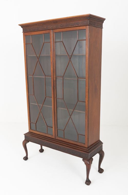 A mahogany Chippendale style glazed bookcase featuring geometric glass door panels, a carved frieze, and cabriole legs ending in ball and claw feet. View IX