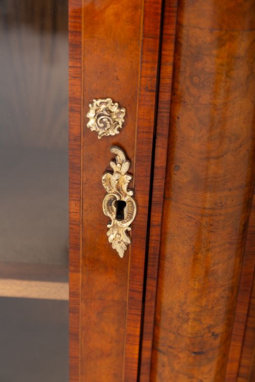 A Victorian burr walnut credenza featuring three arched glazed doors, intricate gilt ormolu mounts, and a solid plinth base. View VI