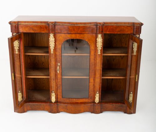 A Victorian burr walnut credenza featuring three arched glazed doors, intricate gilt ormolu mounts, and a solid plinth base. View VII