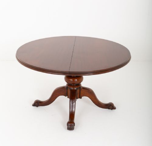 fig 1. An antique Victorian mahogany extending dining table featuring an oval top, removable centre leaf, and a carved central pedestal base with splayed legs.
