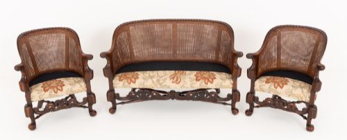 fig 2. A three-piece Carolean style seating suite comprising a settee and two matching armchairs with woven cane backrests, carved scroll stretchers, and floral fabric seat cushions.