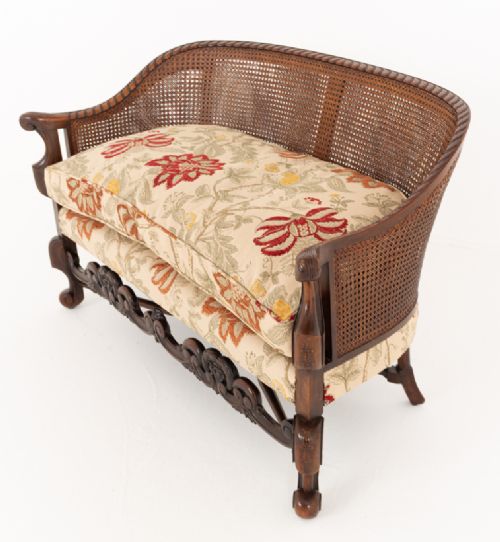 A three-piece Carolean style seating suite comprising a settee and two matching armchairs with woven cane backrests, carved scroll stretchers, and floral fabric seat cushions. View V
