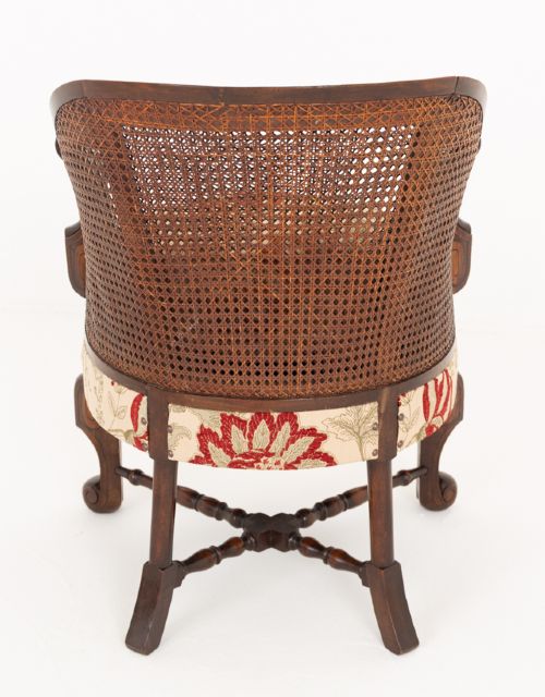 A three-piece Carolean style seating suite comprising a settee and two matching armchairs with woven cane backrests, carved scroll stretchers, and floral fabric seat cushions. View XIV