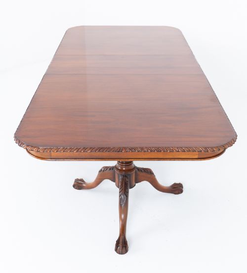 A Regency Revival twin-pedestal mahogany dining table featuring carved edging, turned support pillars, and splayed legs ending in carved feet. View XII