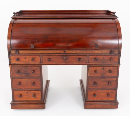fig 1. A Victorian mahogany cylinder desk featuring a curved roll-top hood, multiple pedestal drawers, and turned wooden knobs.