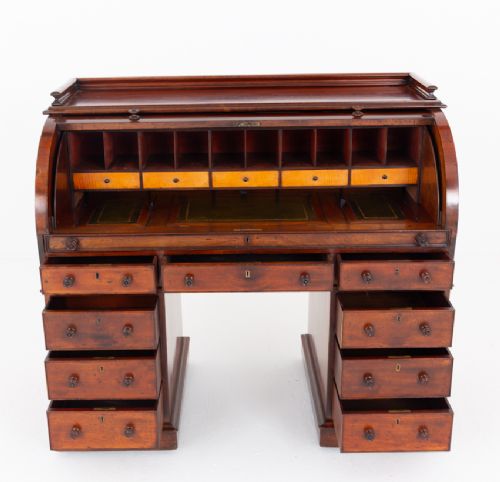 A Victorian mahogany cylinder desk featuring a curved roll-top hood, multiple pedestal drawers, and turned wooden knobs. View VI