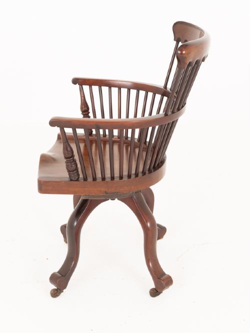 Victorian mahogany swivel desk chair featuring a spindle back, rounded armrests, contoured wooden saddle seat, and splayed legs with castors. View IV