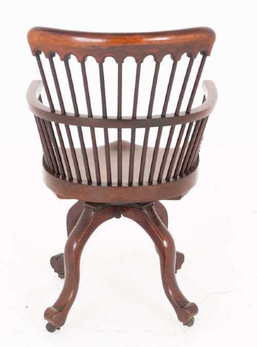 Victorian mahogany swivel desk chair featuring a spindle back, rounded armrests, contoured wooden saddle seat, and splayed legs with castors. View V