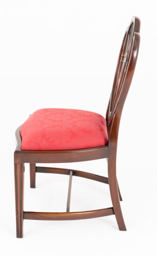 A set of twelve mahogany dining chairs with carved Prince of Wales plume backs and red damask fabric seats arranged in a arc. View VI