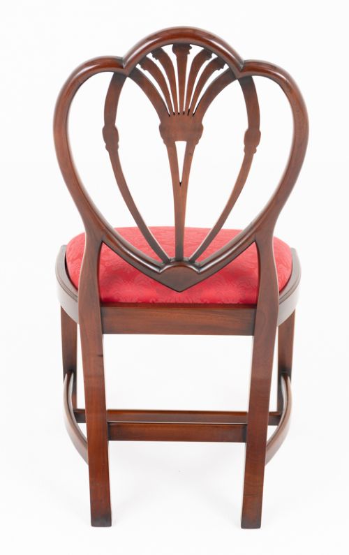 A set of twelve mahogany dining chairs with carved Prince of Wales plume backs and red damask fabric seats arranged in a arc. View VIII