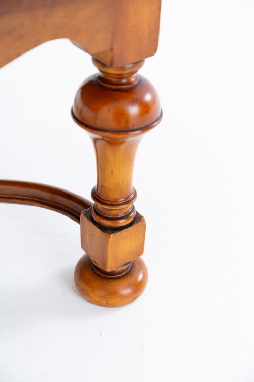 A square low coffee table crafted from warm brown burr walnut veneer with crossbanded borders, turned baluster legs, and curved stretchers. View IV