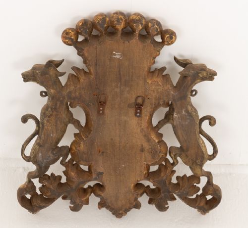 A gilded hardwood armorial shield featuring central cross quarterings flanked by two hound supporters and crowned with a ball-adorned coronet. View V