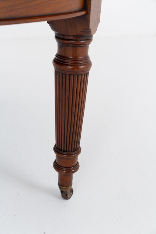 An extended oval walnut dining table with fluted turned legs ending in brass castors. View III