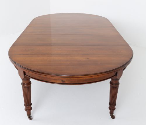 An extended oval walnut dining table with fluted turned legs ending in brass castors. View X