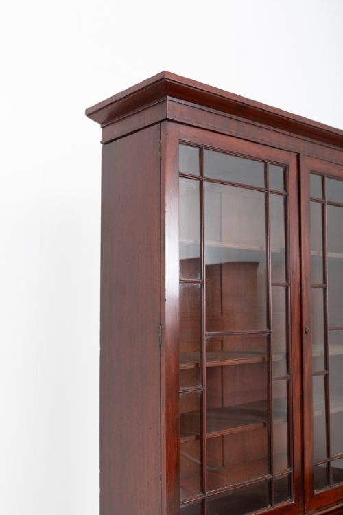 fig 1. A William IV mahogany secretaire bookcase featuring an upper cabinet with astragal glazed doors, a pull-down secretaire drawer with brass lion mask handles, and a lower two-door cupboard.