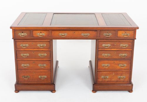 fig 1. A Victorian mahogany pedestal desk featuring a green leather inset writing surface, multiple drawers with brass handles, and a plinth base.
