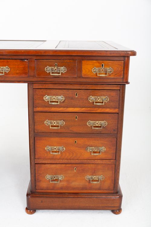 fig 2. A Victorian mahogany pedestal desk featuring a green leather inset writing surface, multiple drawers with brass handles, and a plinth base.