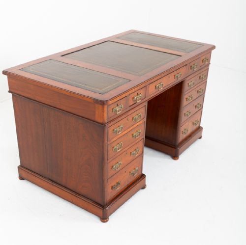 A Victorian mahogany pedestal desk featuring a green leather inset writing surface, multiple drawers with brass handles, and a plinth base. View IV
