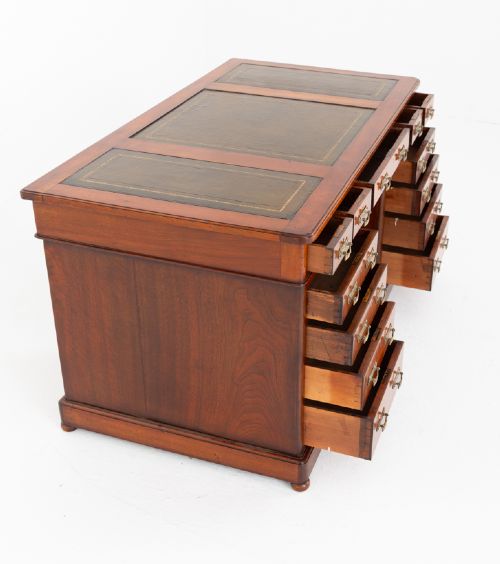 A Victorian mahogany pedestal desk featuring a green leather inset writing surface, multiple drawers with brass handles, and a plinth base. View VII