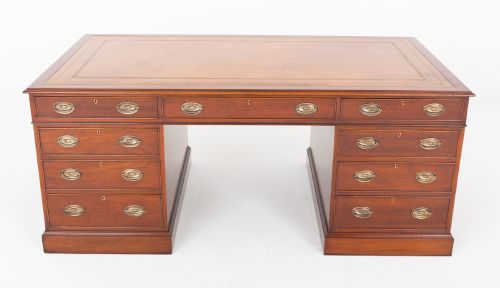 fig 1. A Georgian style mahogany partners desk featuring a tan leather writing surface, multiple drawers with oval brass handles, and twin pedestal supports.